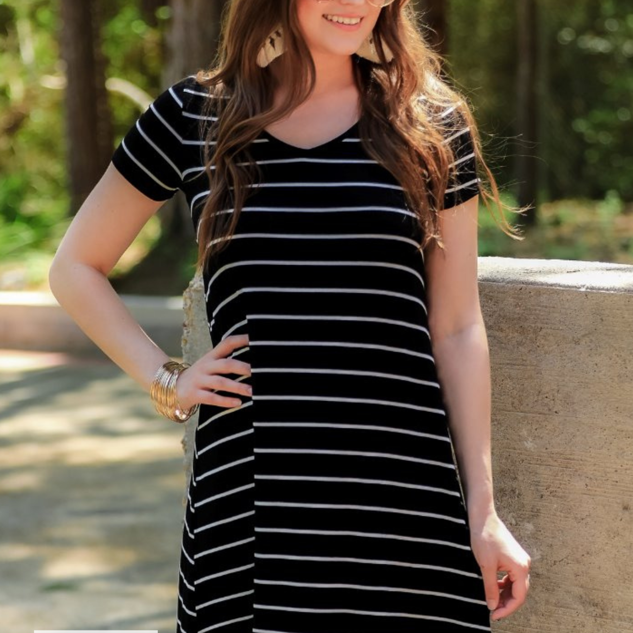 a soft stretchy knit dress with a V-neckline, short sleeves, a relaxed A-line silhouette, a straight hemline, and a horizontal white stripe pattern on a solid black background with a MADE IN USA watermark in the bottom left hand corner