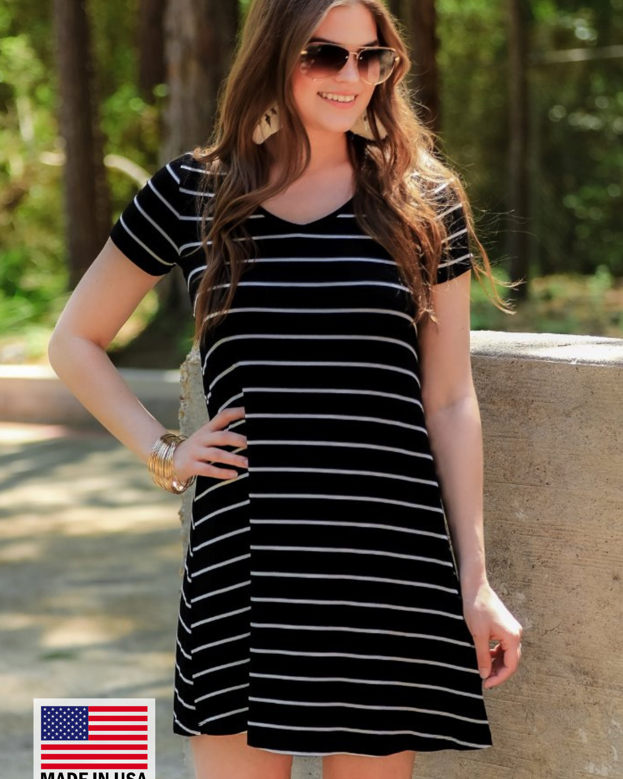 a soft stretchy knit dress with a V-neckline, short sleeves, a relaxed A-line silhouette, a straight hemline, and a horizontal white stripe pattern on a solid black background with a MADE IN USA watermark in the bottom left hand corner
