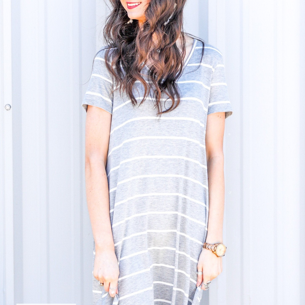 a soft stretchy knit dress with a V-neckline, short sleeves, a relaxed A-line silhouette, a straight hemline, and a horizontal white stripe pattern on a solid heathered grey background with a MADE IN USA watermark in the bottom left hand corner