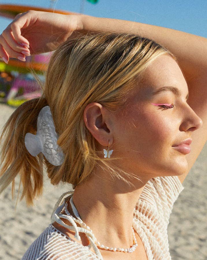 Woman with a ponytail wearing a white hair clip on a beach.