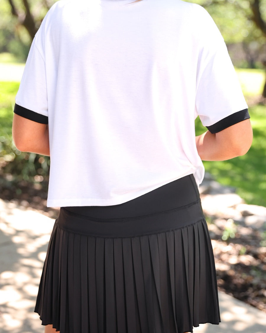 a black pleated tennis skort with built-in shorts, wide comfort waistband, 4-way stretch, and moisture-wicking polyester/spandex blend fabric