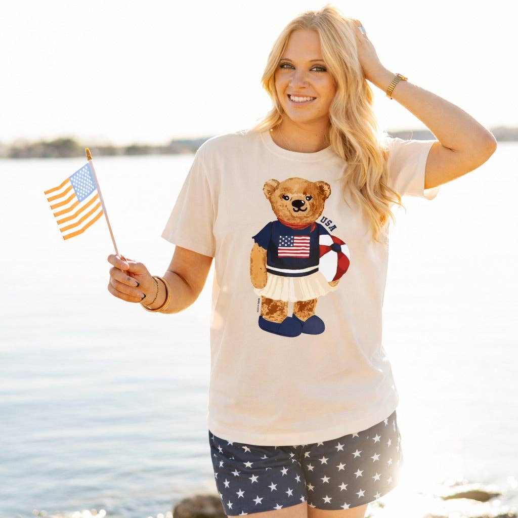 a relaxed-fit beige crew neck tee with a patriotic DTF teddy graphic, short sleeves, standard t-shirt length, unlined construction, and a little stretch that runs large
