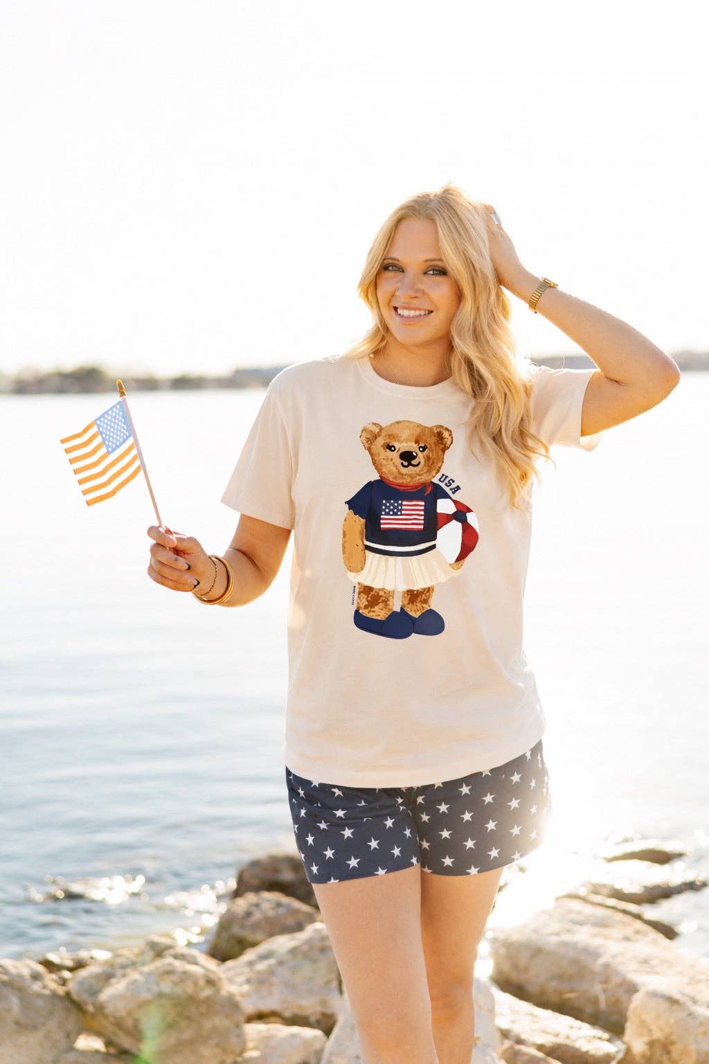 a relaxed-fit beige crew neck tee with a patriotic DTF teddy graphic, short sleeves, standard t-shirt length, unlined construction, and a little stretch that runs large