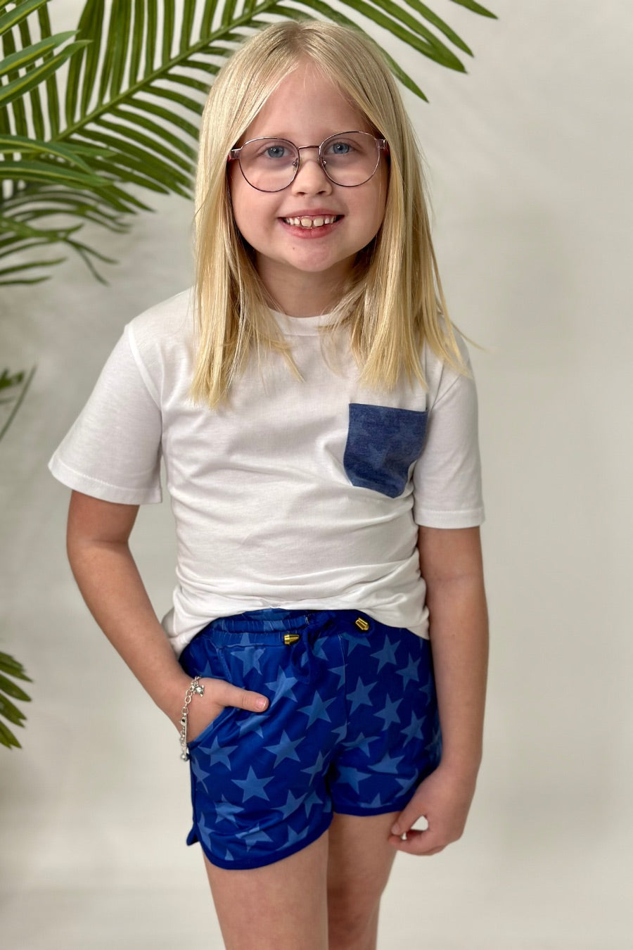 mid-rise relaxed fit activewear shorts with side pockets and a tie waist drawstring with gold bead accents, designed on a blue star-patterned print fabric, royal blue base, and royal blue trims