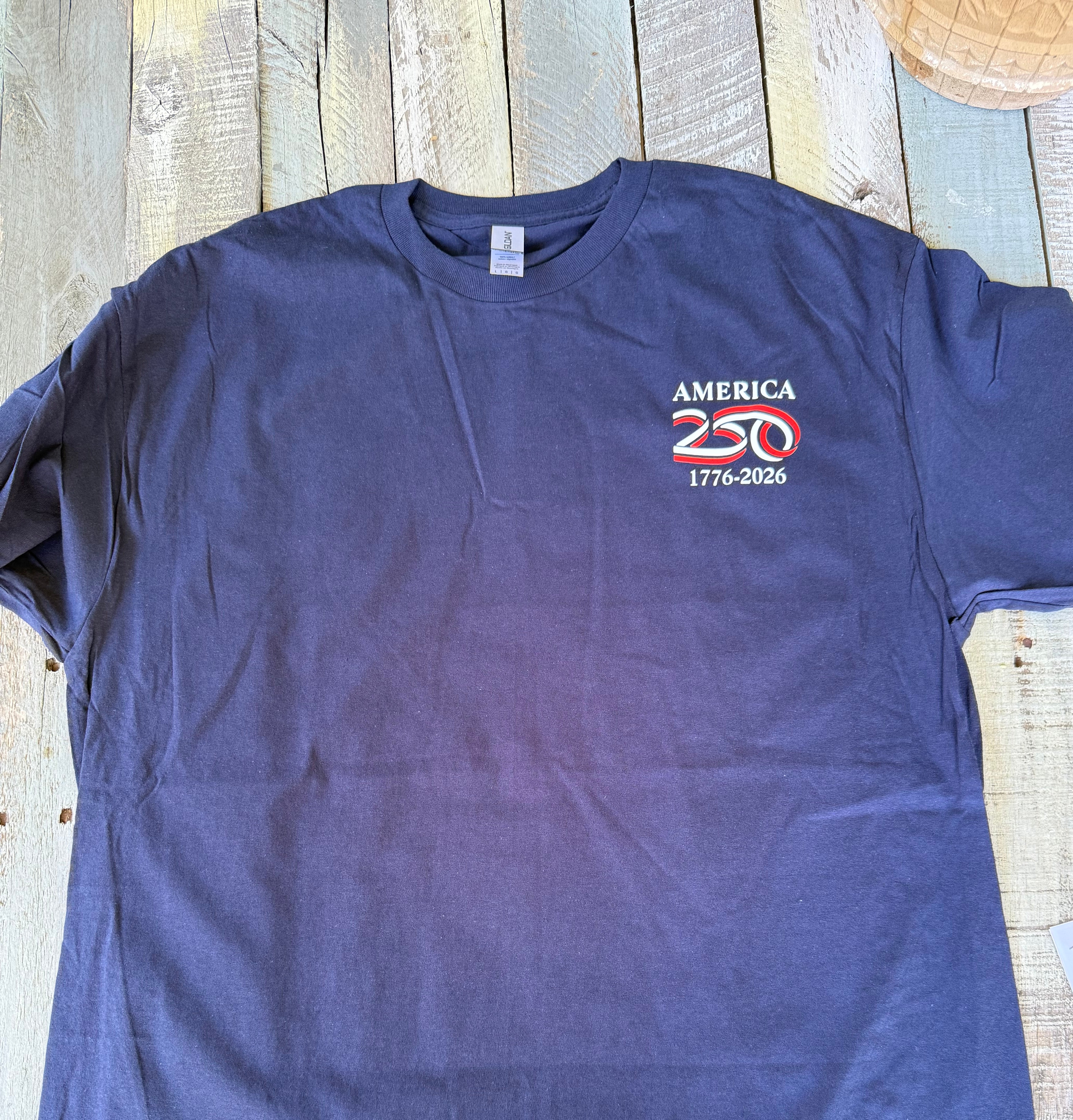a soft navy unisex Gildan t-shirt with a crew neckline, short sleeves, a front America 250 chest graphic, a bold 1776 America back design, a 250 Years of Freedom detail, and an easy year-round fit