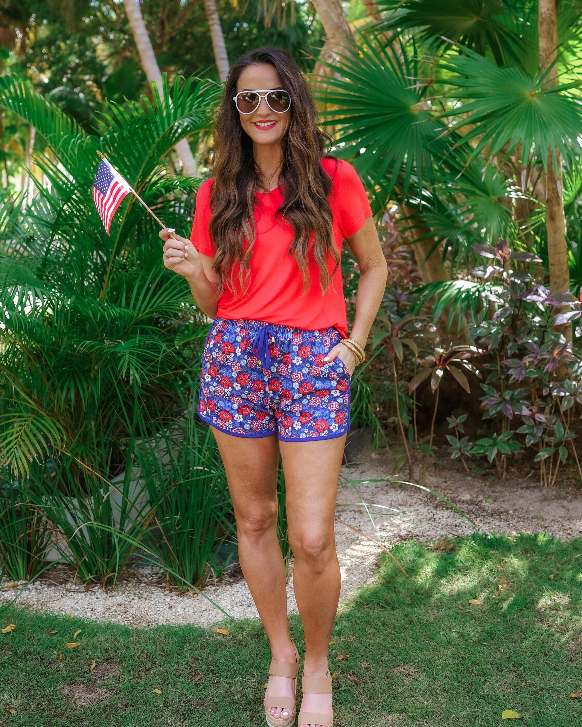 mid-rise relaxed fit activewear shorts with side pockets and a tie waist drawstring with gold bead accents, designed on a patriotic floral (red, white, and blue) pattern print fabric, royal blue base, and royal blue trim