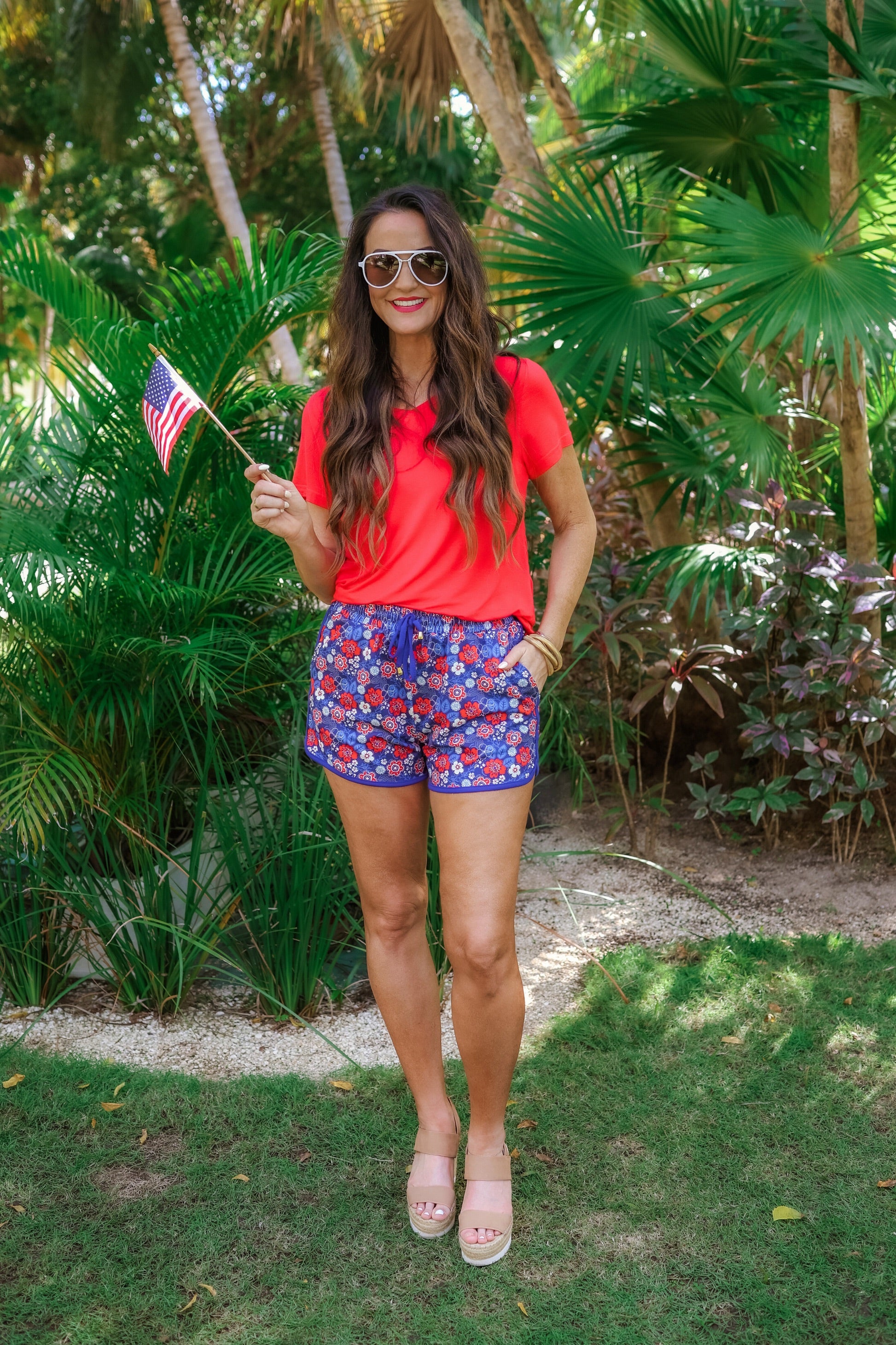 mid-rise relaxed fit activewear shorts with side pockets and a tie waist drawstring with gold bead accents, designed on a patriotic floral (red, white, and blue) pattern print fabric, royal blue base, and royal blue trim