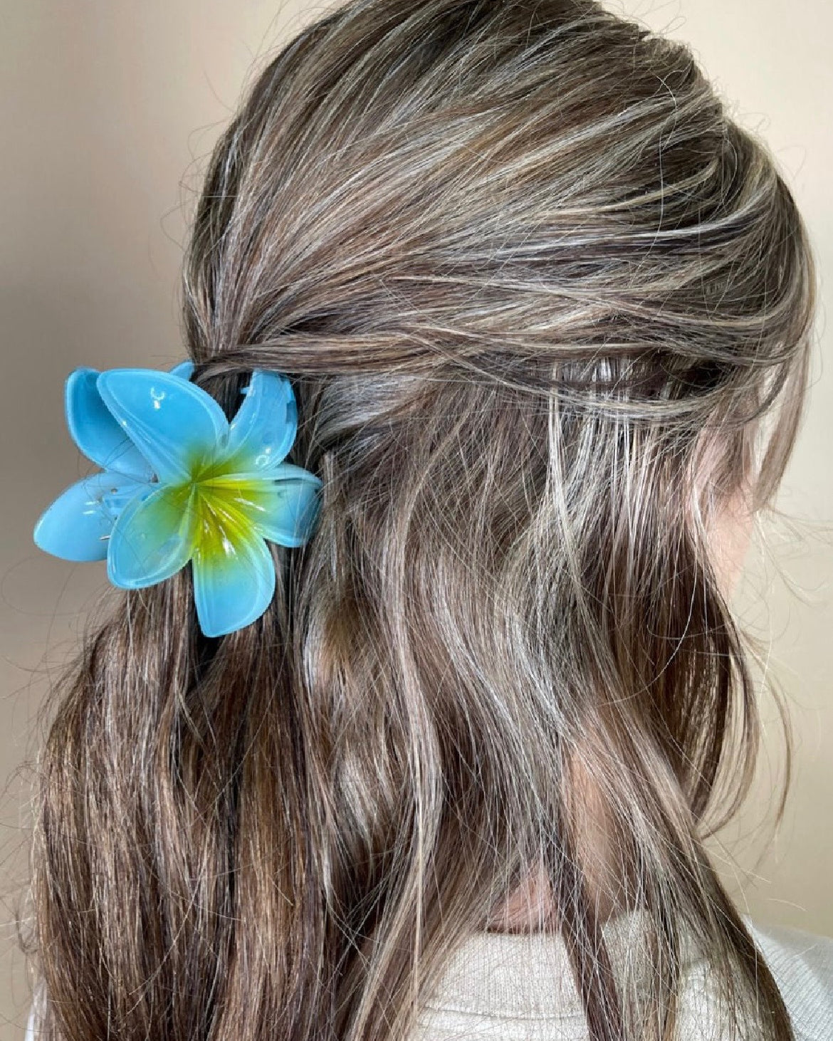 Person with blue flower hair accessory against a neutral background