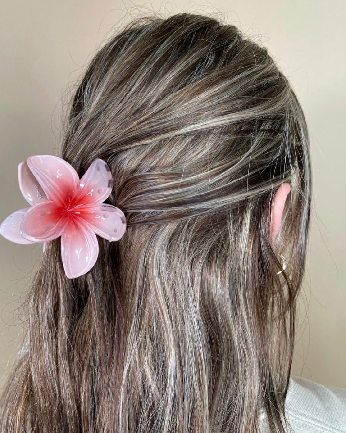 Person with blush flower hair accessory against a neutral background