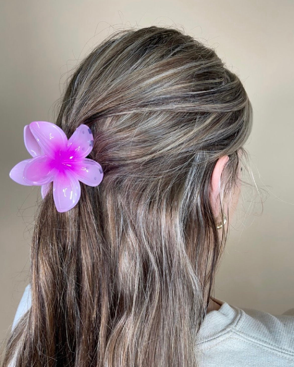 Person with pink flower hair accessory against a neutral background