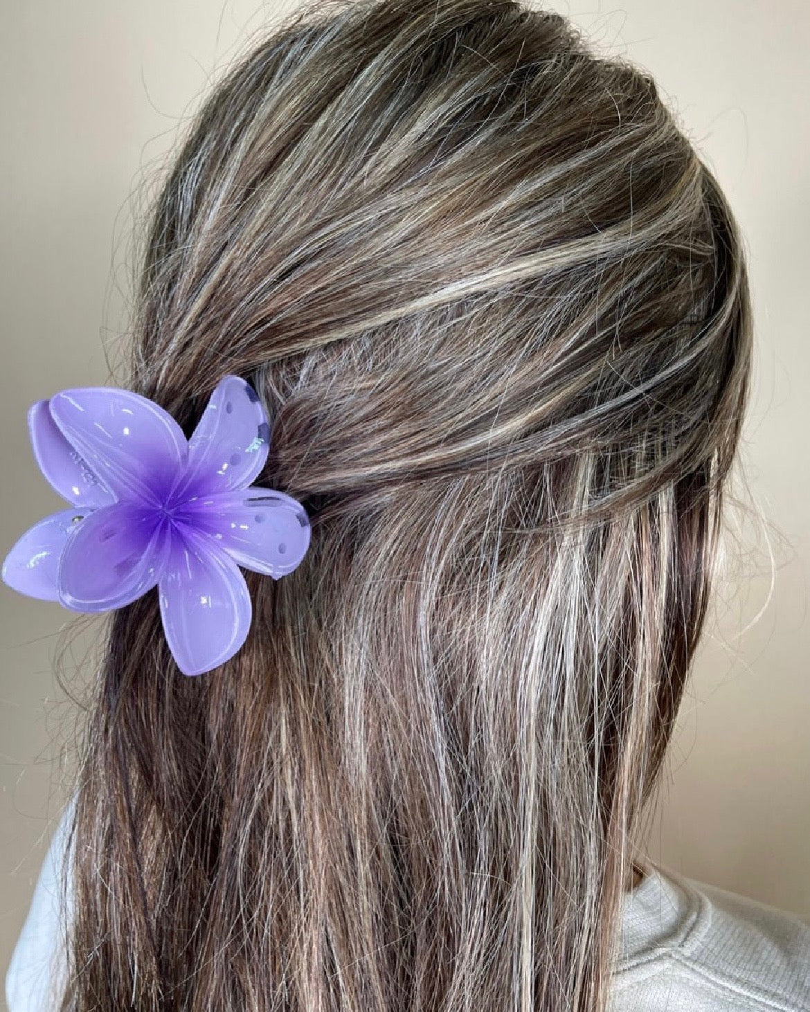 Person with purple flower hair accessory against a neutral background