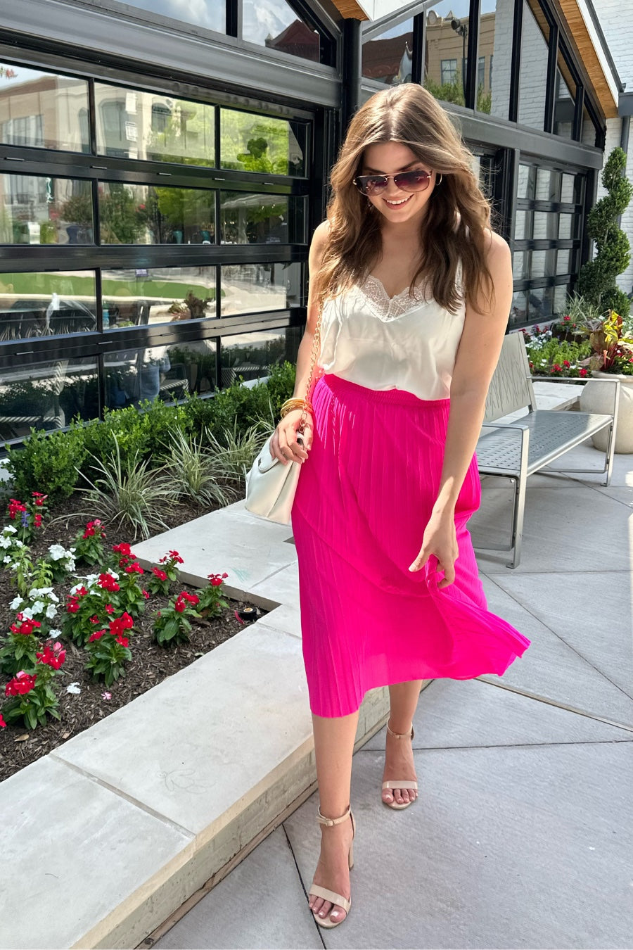 a vibrant pink midi skirt with an elastic waistband, a graceful pleated design, and an interior lining slip
