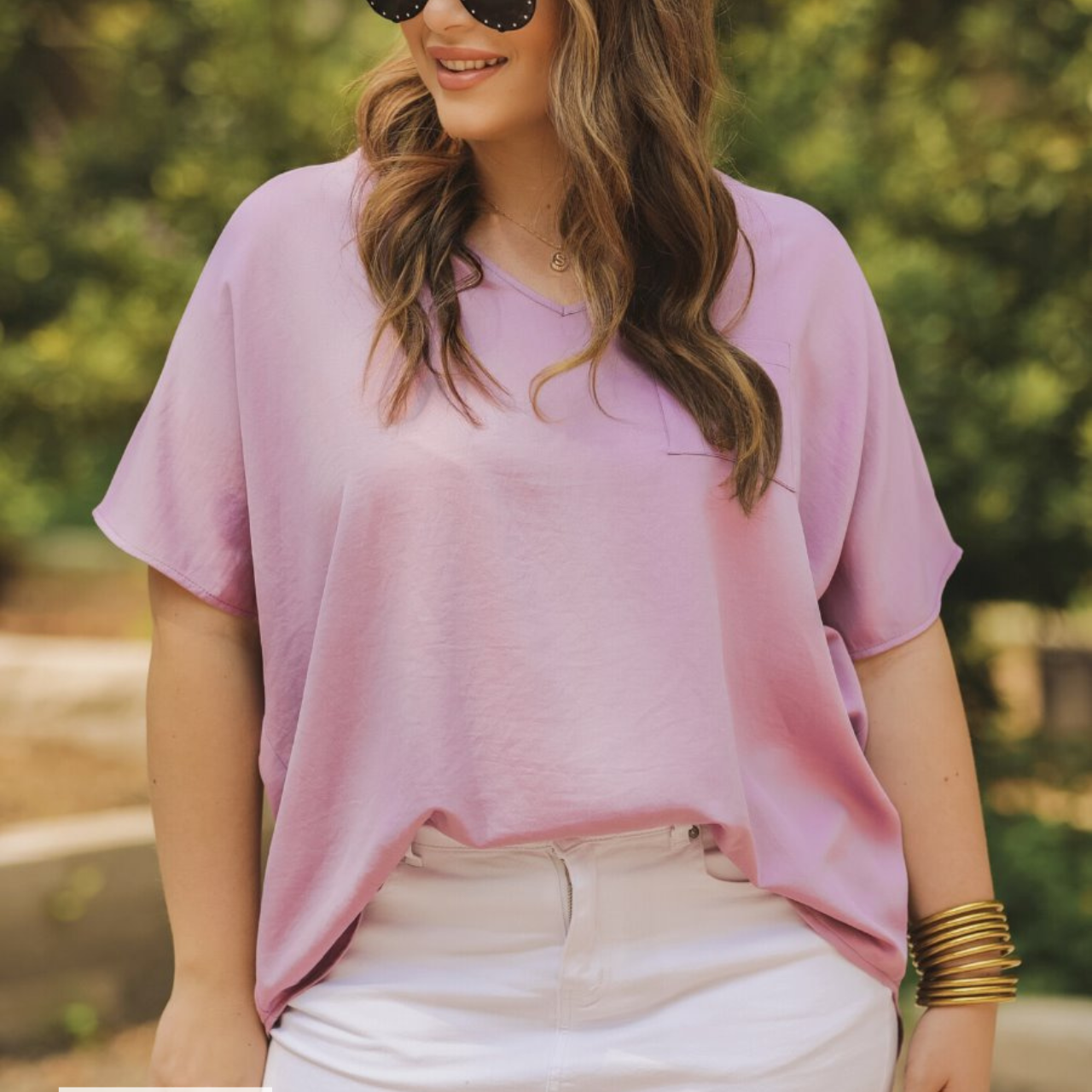 a lightweight lilac short-sleeve woven tunic with a V-neckline, a front chest pocket, and a relaxed, non-stretch silhouette, accented with a MADE IN USA watermark in the bottom left-hand corner