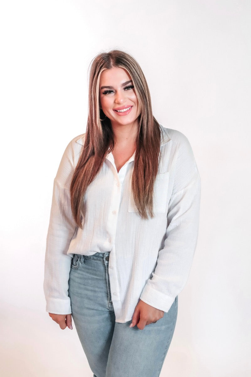 white lightweight button-up gauze top with a collared neckline, breezy sleeves, chest pocket, and a relaxed round-hem silhouette