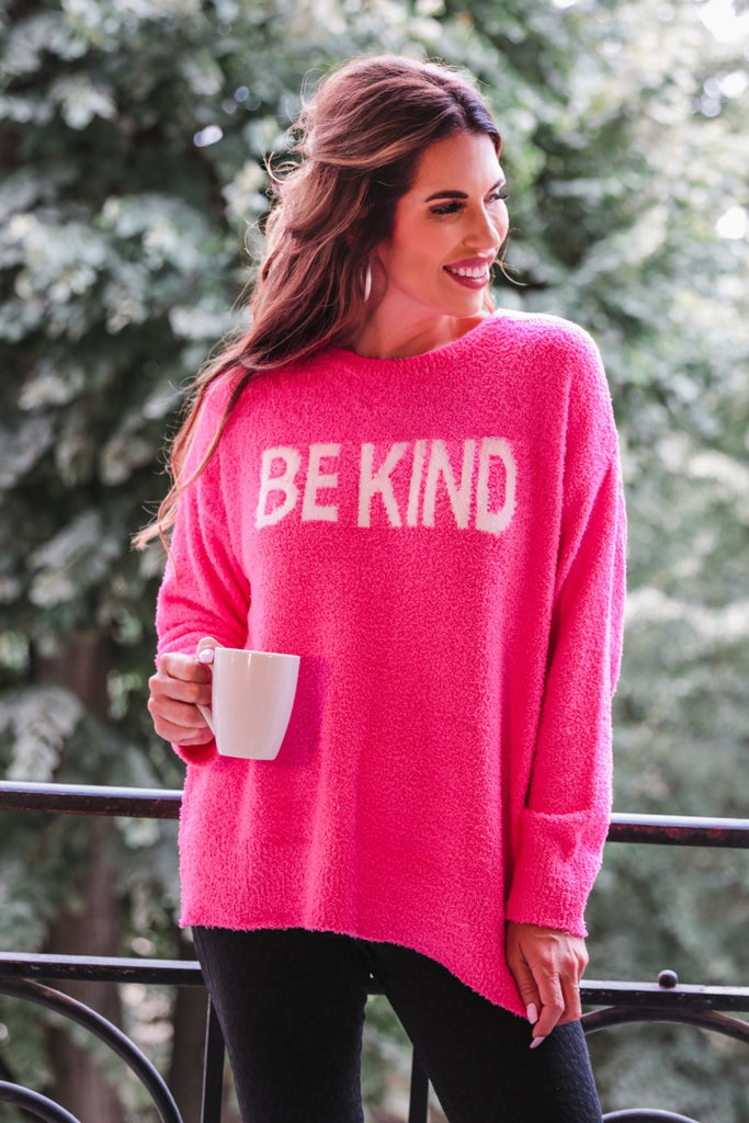 pink sweater made of blanket material with long sleeves & "BE KIND" wording in white