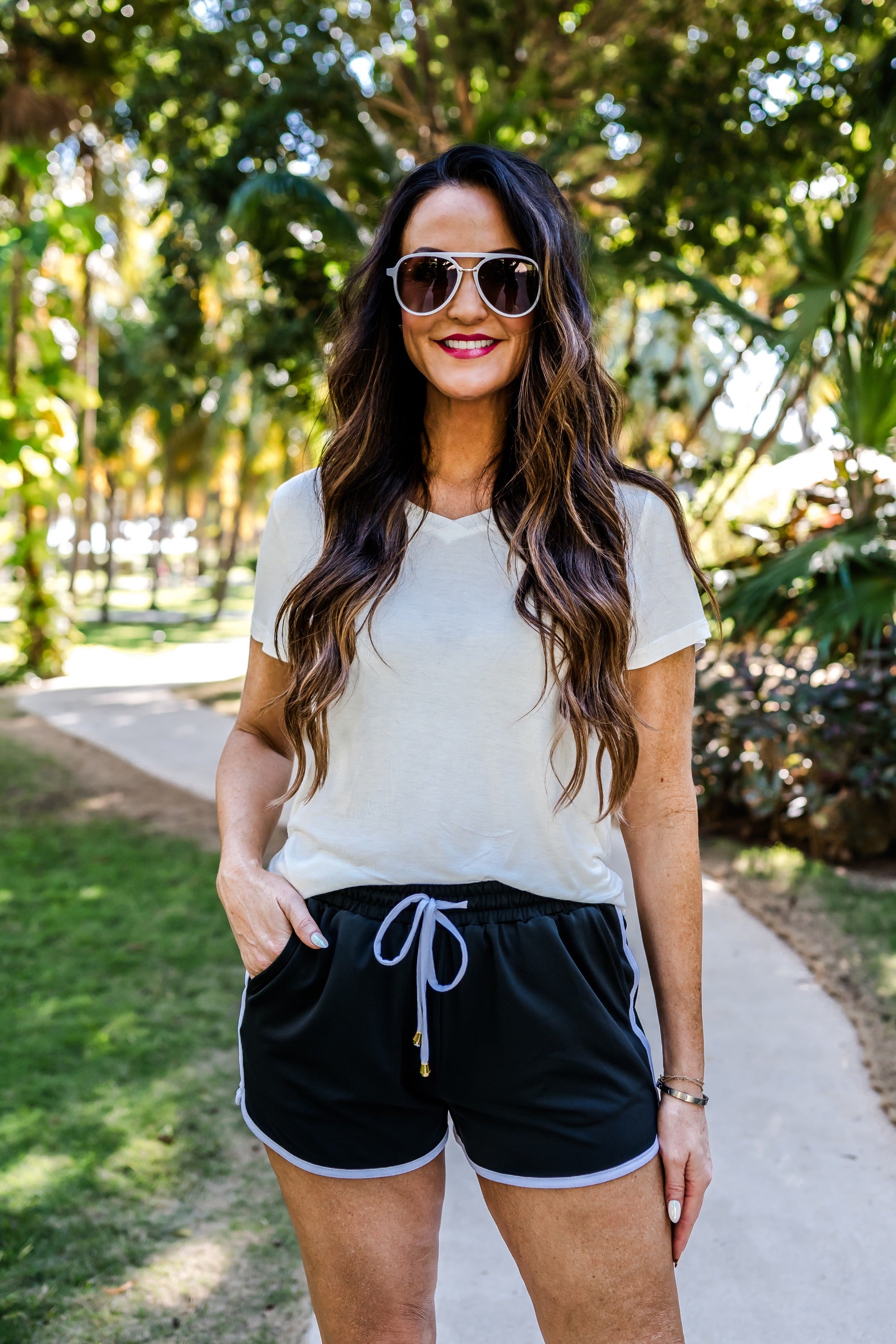 mid-rise relaxed fit activewear shorts with side pockets and a tie waist drawstring with gold bead accents, designed on a solid black print fabric and white trim