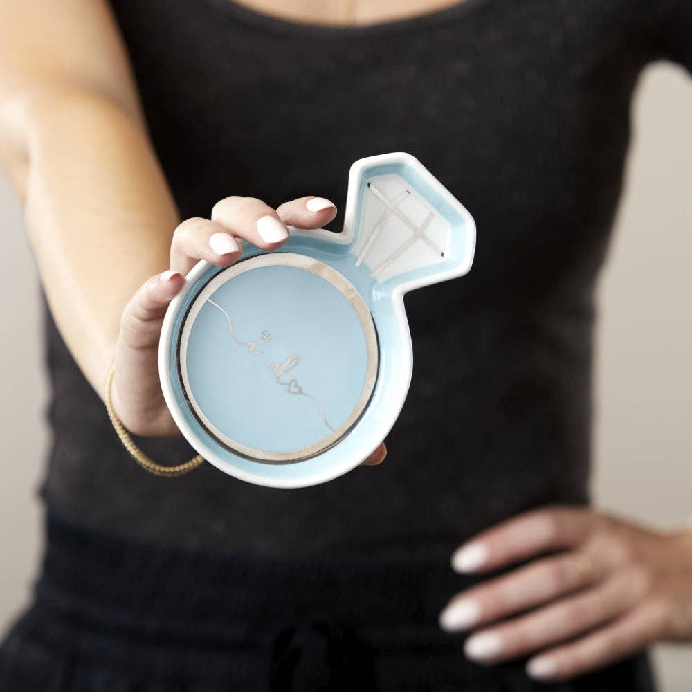 Person holding a blue and white decorative item shaped like a female symbol.