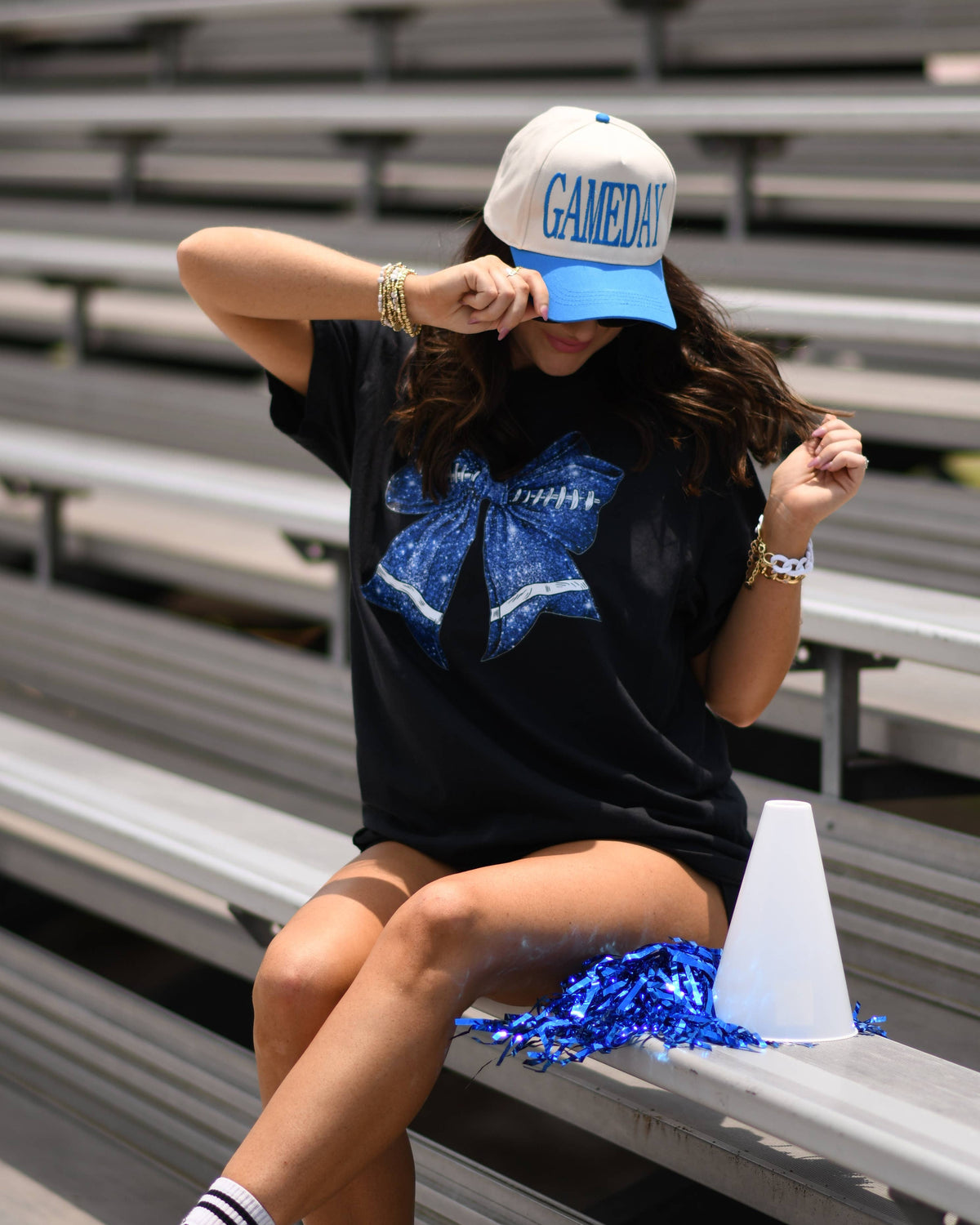 a black Comfort Colors tee crafted on soft garment-dyed cotton with a DTF-printed blue faux glitter football bow graphic, crew neckline, and short sleeves in both youth and adult sizing
