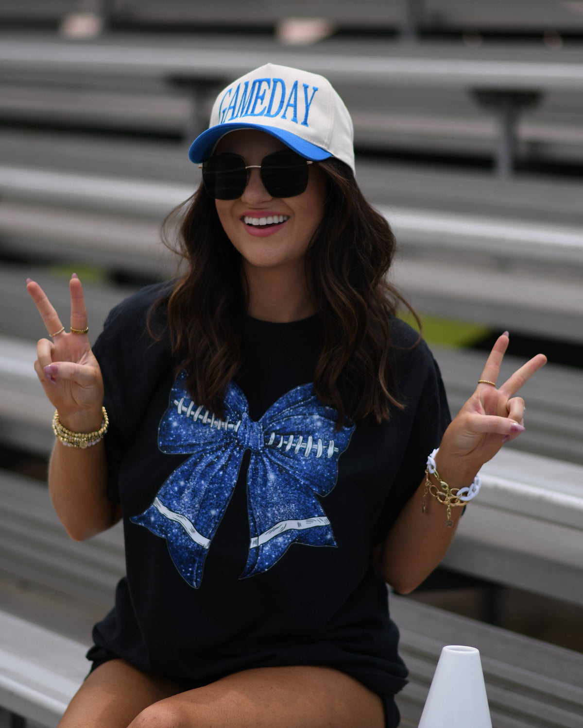 a black Comfort Colors tee crafted on soft garment-dyed cotton with a DTF-printed blue faux glitter football bow graphic, crew neckline, and short sleeves in both youth and adult sizing