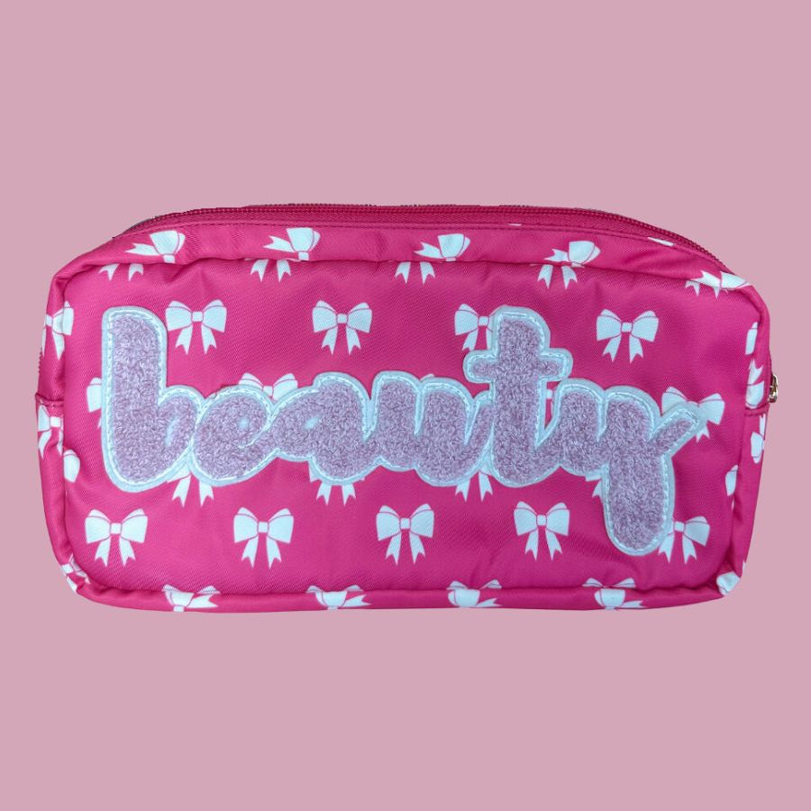white bow pattern on a neon pink background travel bag with a zipper closure and a chenille patch bearing BEAUTY
