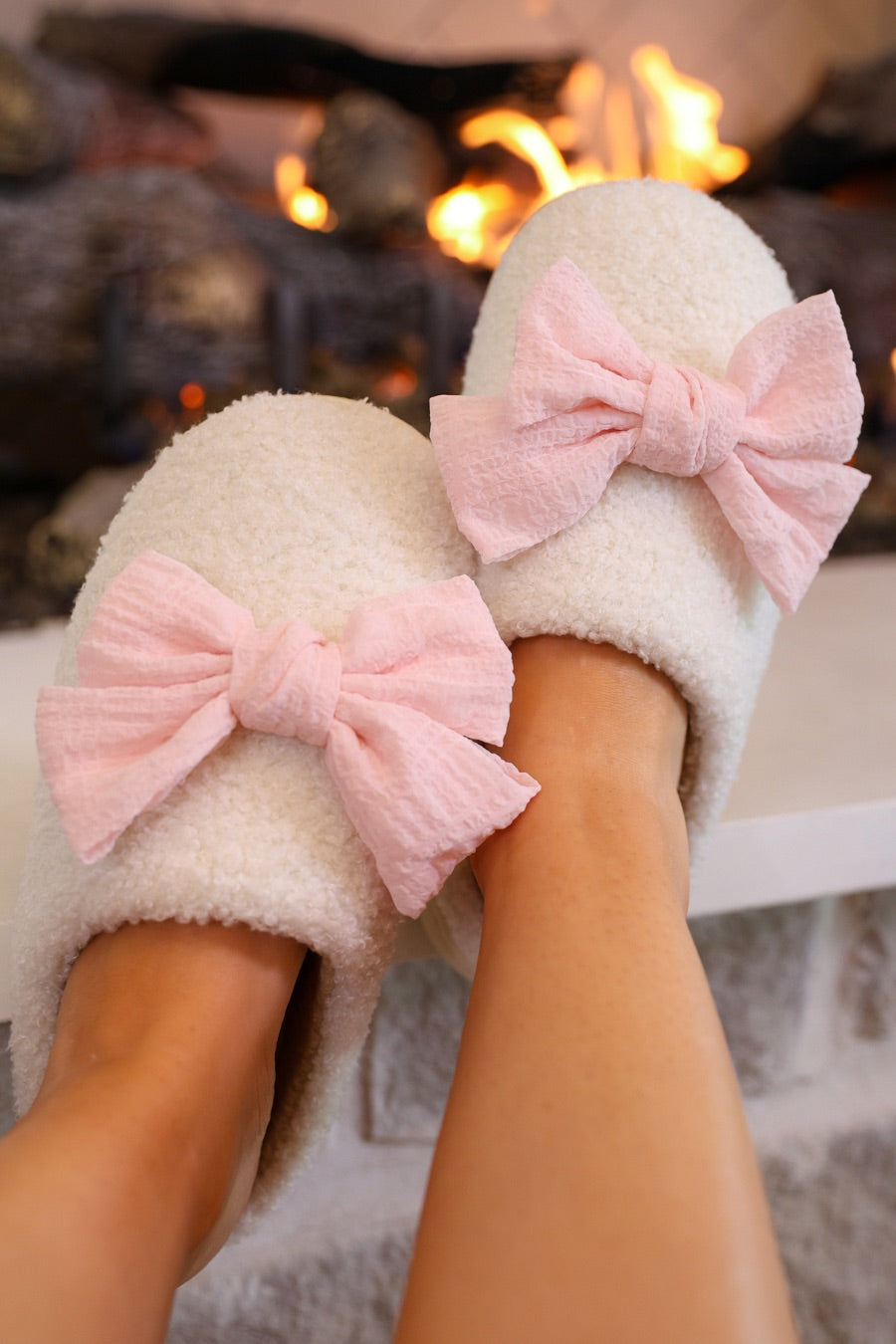 soft white plush slippers with a cozy cushioned sole and an oversized pink bow detail