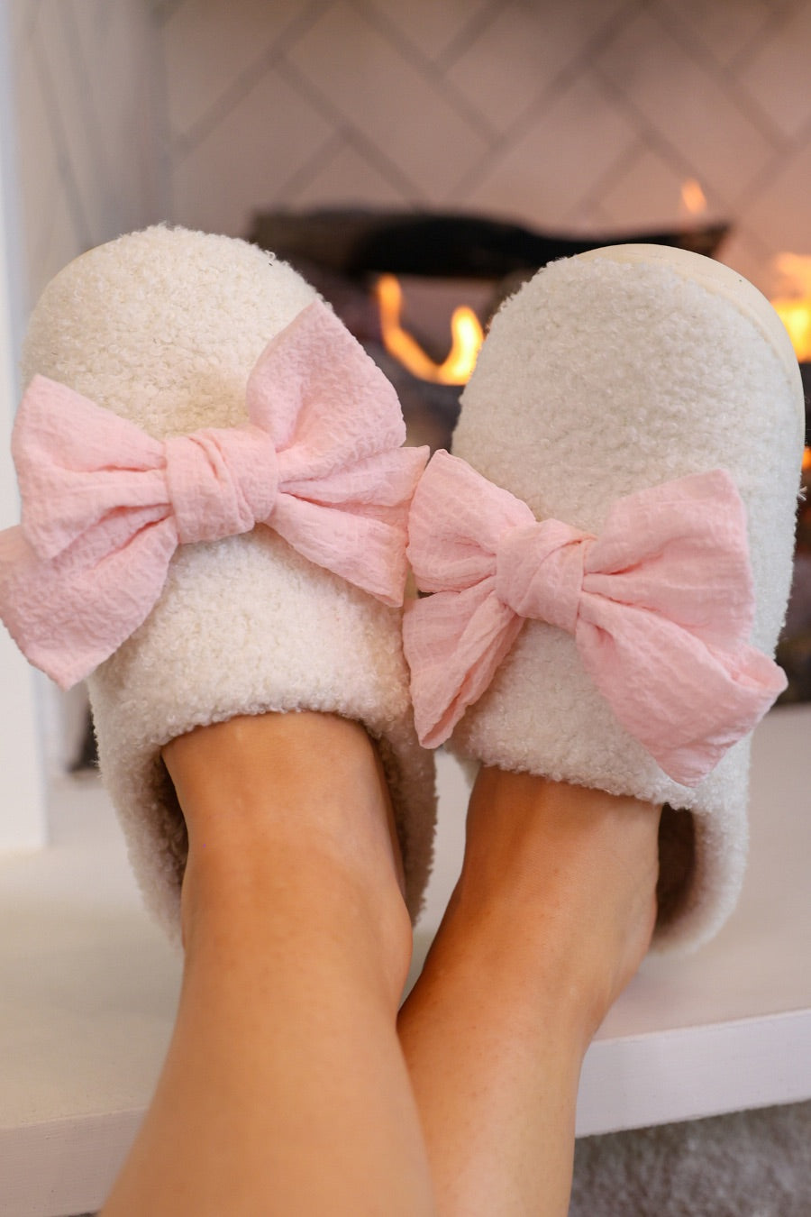 soft white plush slippers with a cozy cushioned sole and an oversized pink bow detail