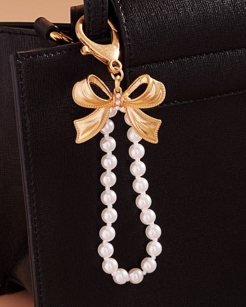 Gold bow and pearl charm on a black handbag