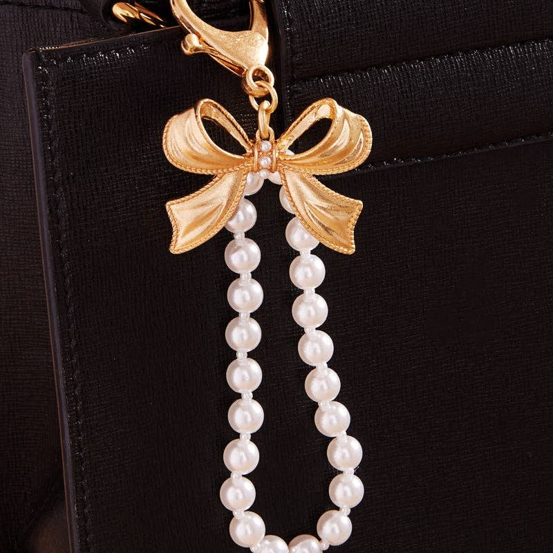 Gold bow and pearl charm on a black handbag