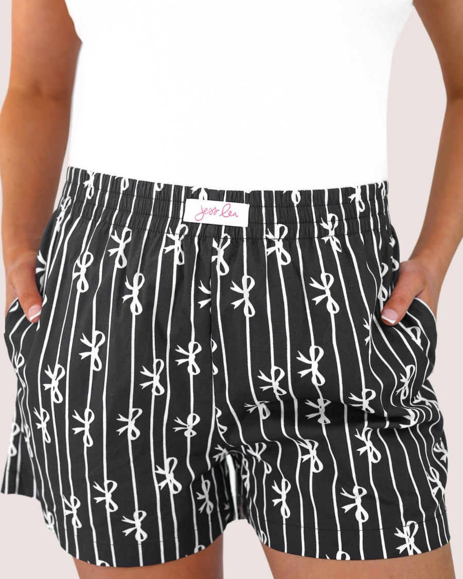 mid-rise relaxed fit boxer shorts with side pockets and an elastic waistband, designed on a bow and stripe pattern print and a solid base in black