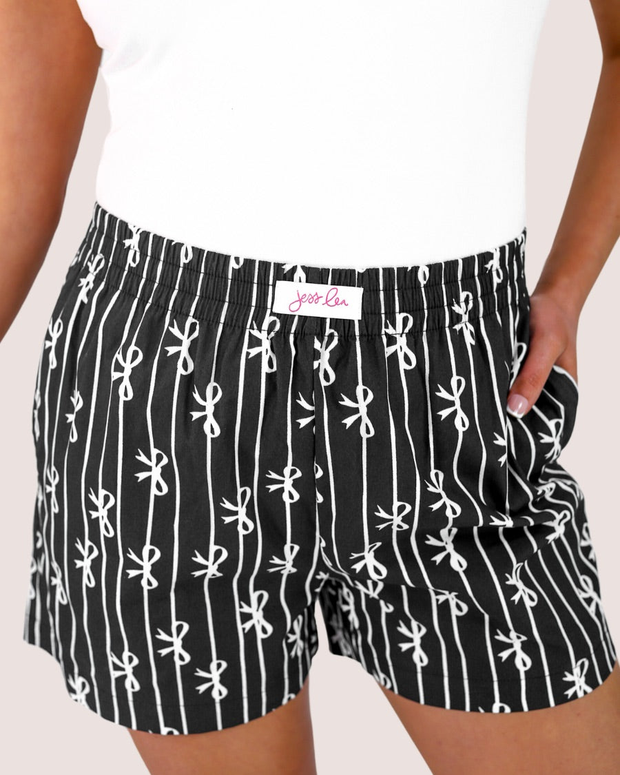 mid-rise relaxed fit boxer shorts with side pockets and an elastic waistband, designed on a bow and stripe pattern print and a solid base in black