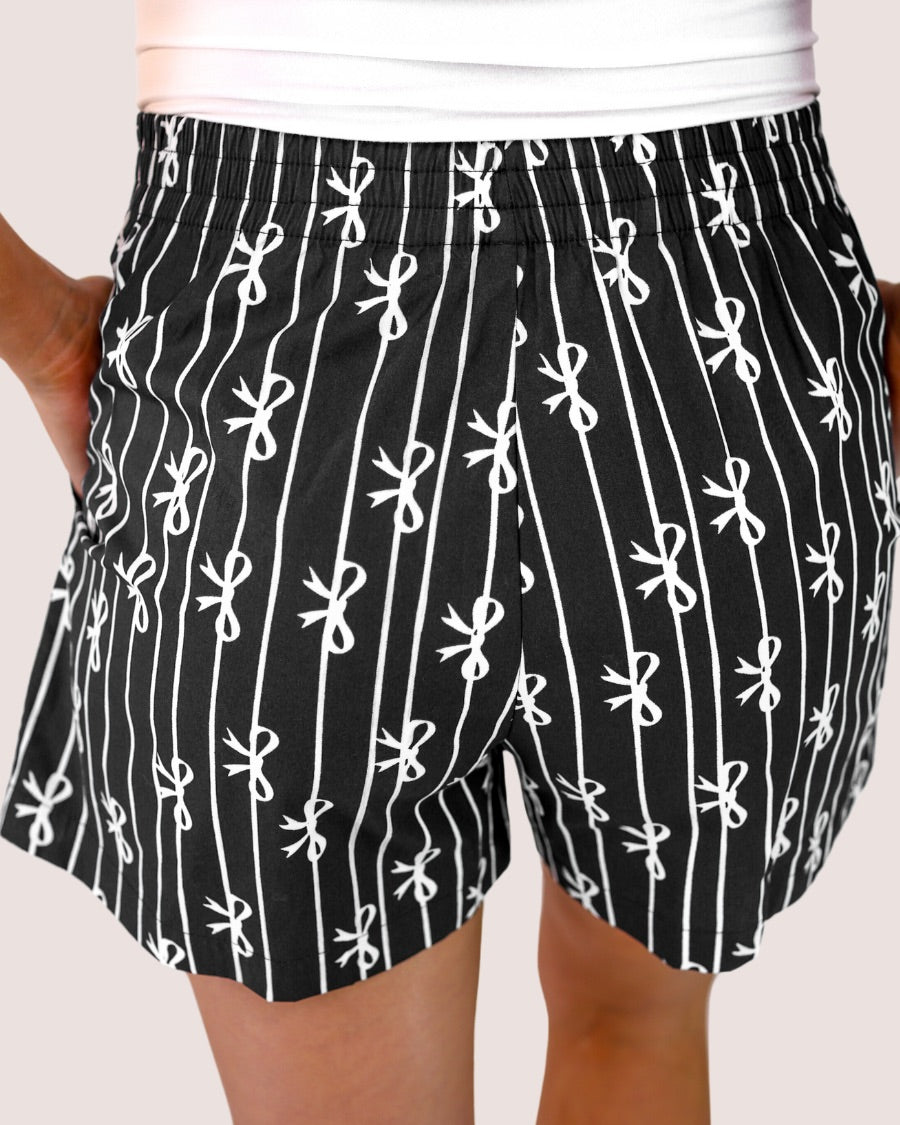 mid-rise relaxed fit boxer shorts with side pockets and an elastic waistband, designed on a bow and stripe pattern print and a solid base in black