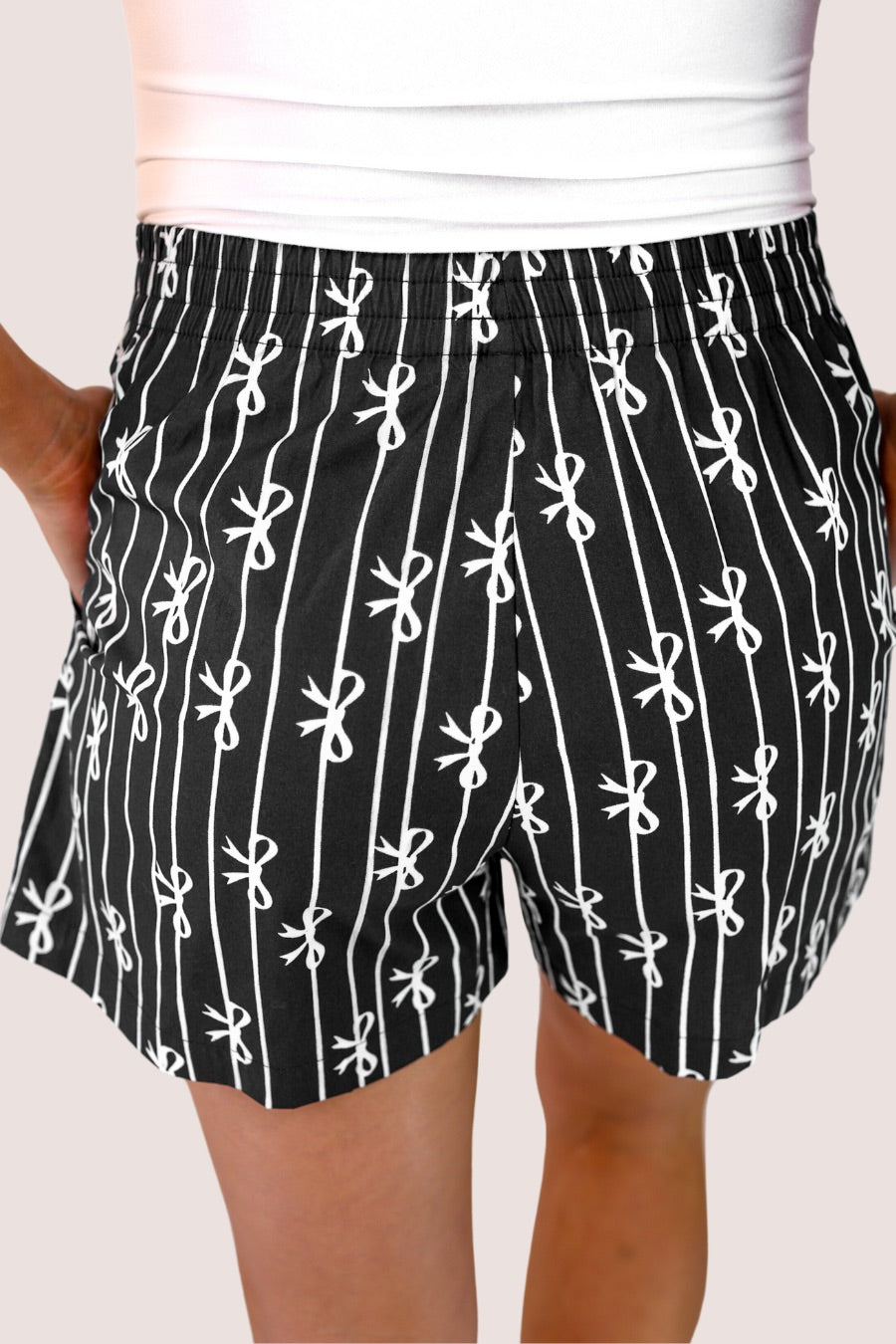mid-rise relaxed fit boxer shorts with side pockets and an elastic waistband, designed on a bow and stripe pattern print and a solid base in black