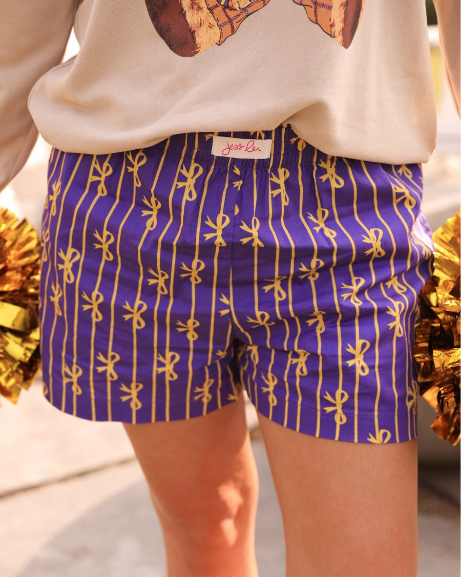 mid-rise relaxed fit boxer shorts with side pockets and an elastic waistband, designed on a bow and stripe pattern print and a solid base in purple