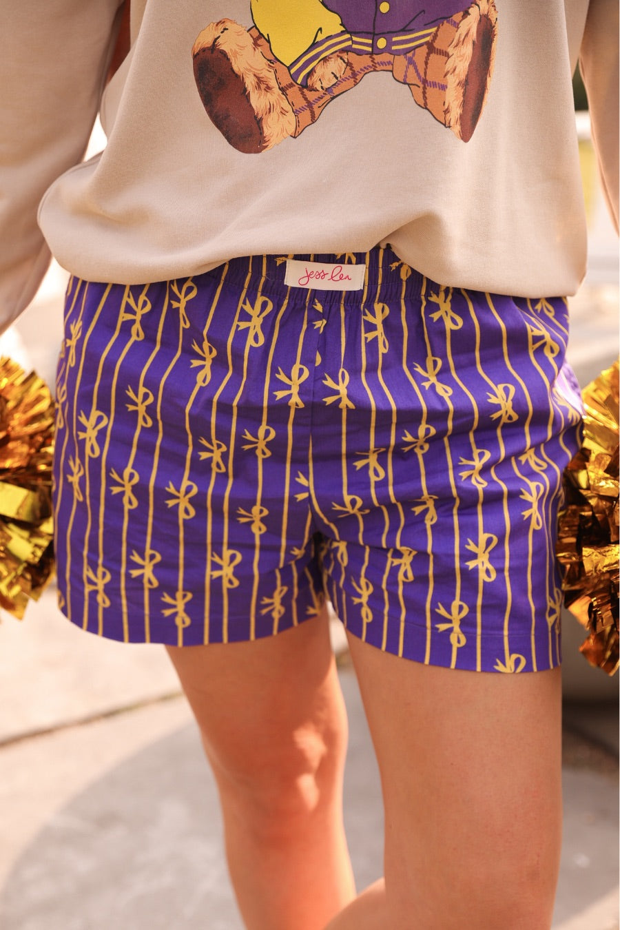 mid-rise relaxed fit boxer shorts with side pockets and an elastic waistband, designed on a bow and stripe pattern print and a solid base in purple