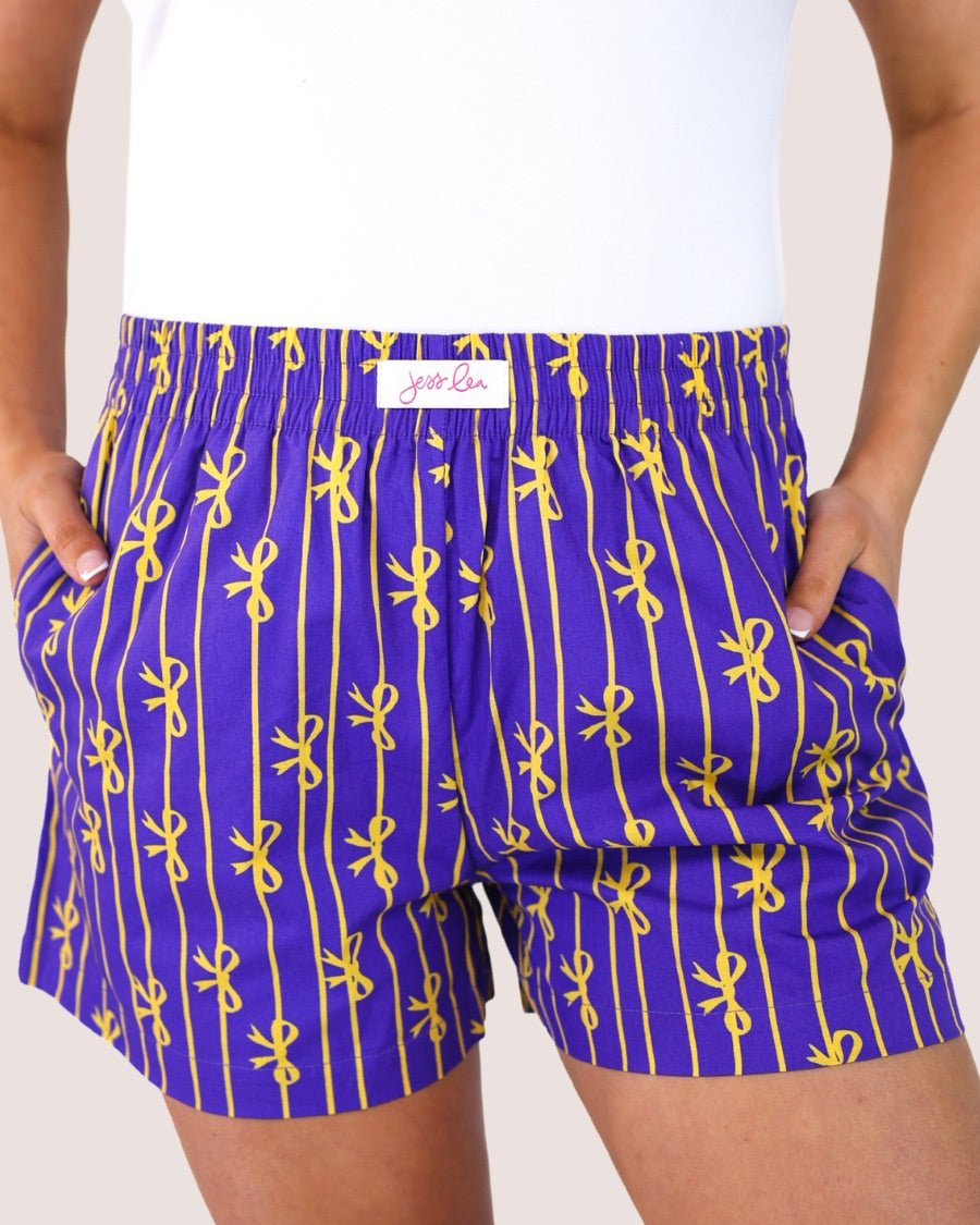 mid-rise relaxed fit boxer shorts with side pockets and an elastic waistband, designed on a bow and stripe pattern print and a solid base in purple