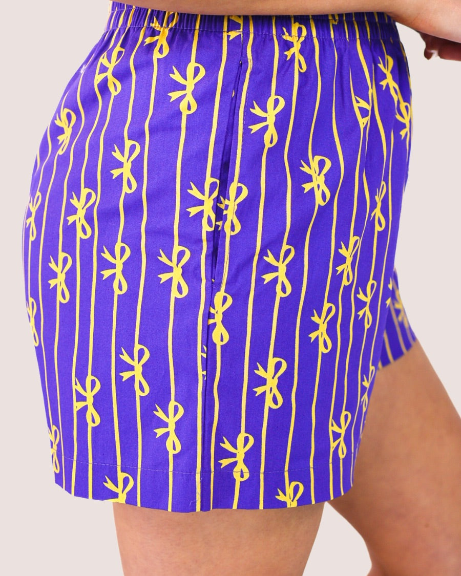 mid-rise relaxed fit boxer shorts with side pockets and an elastic waistband, designed on a bow and stripe pattern print and a solid base in purple