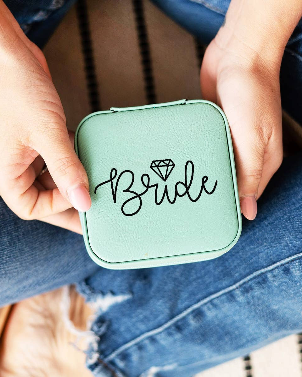 Green compact mirror with 'Bride' text held by a person wearing blue jeans.
