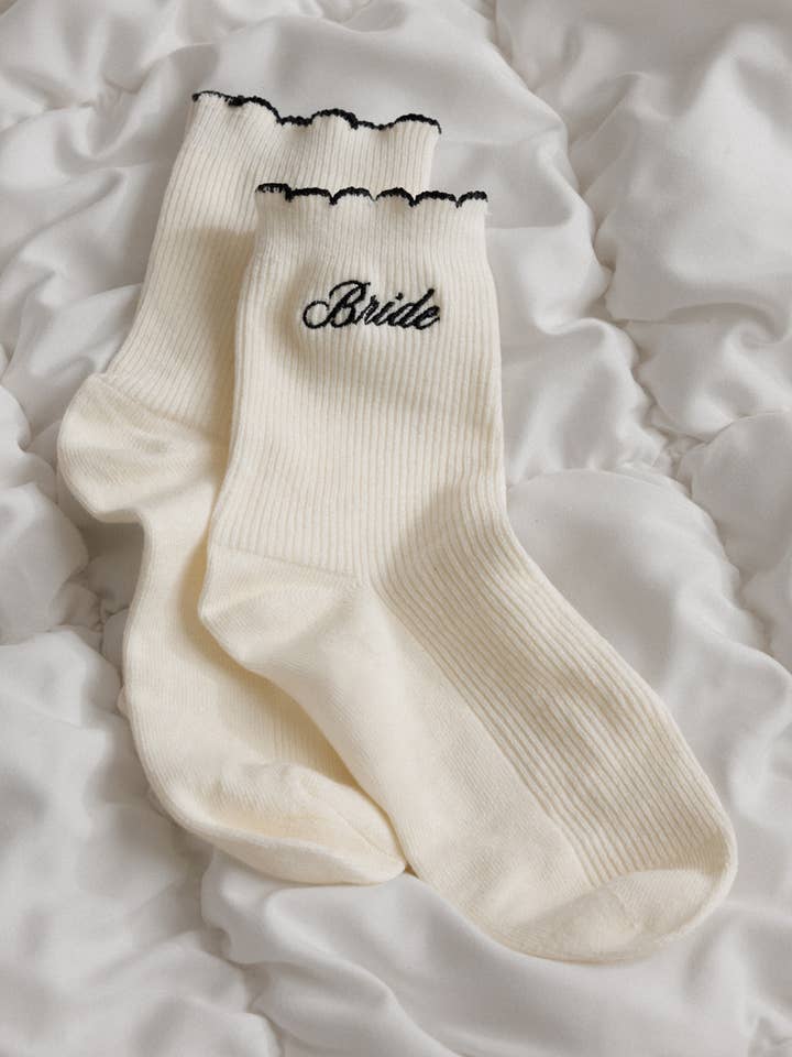 White socks with 'Bride' embroidery on a white fabric background