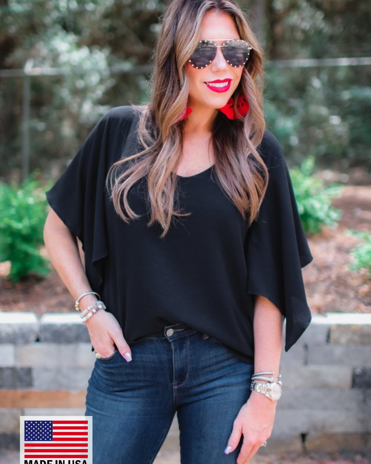 a black v-neck blouses crafted from lightweight textured fabric with asymmetrical half-flutter sleeves, front lining, and a relaxed fit, accented by a MADE IN USA watermark in the bottom left-hand corner