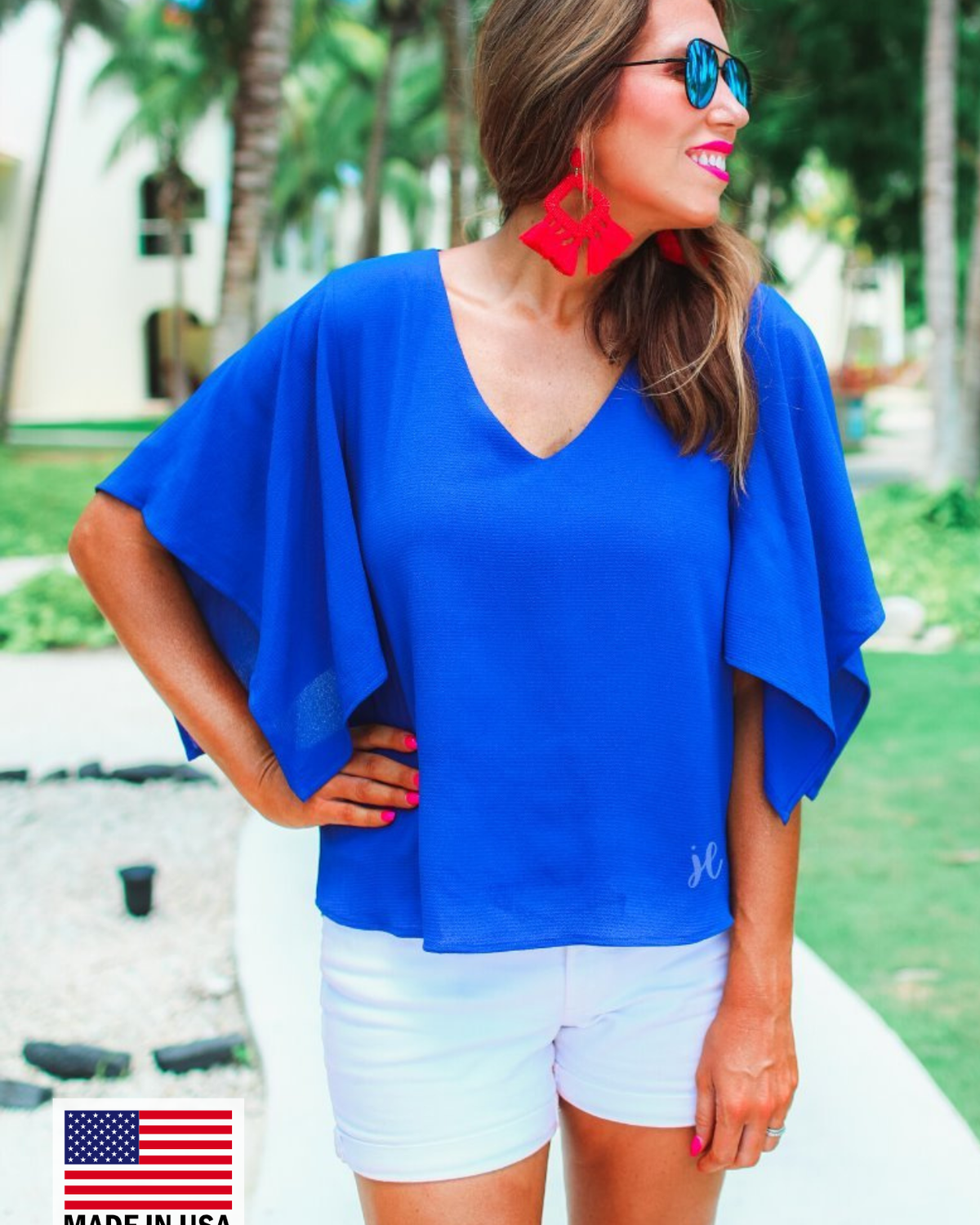 a blue v-neck blouses crafted from lightweight textured fabric with asymmetrical half-flutter sleeves, front lining, and a relaxed fit, accented by a MADE IN USA watermark in the bottom left-hand corner