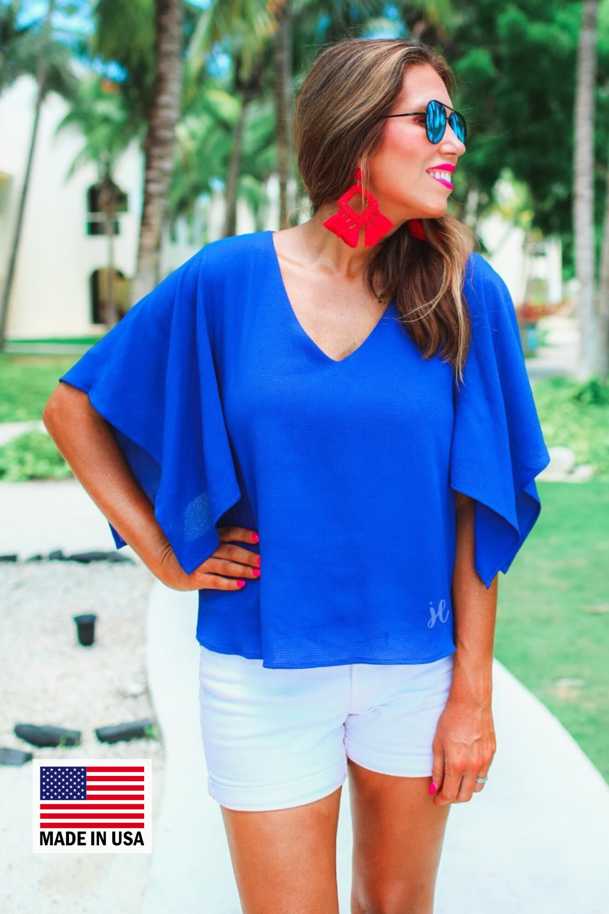 a blue v-neck blouses crafted from lightweight textured fabric with asymmetrical half-flutter sleeves, front lining, and a relaxed fit, accented by a MADE IN USA watermark in the bottom left-hand corner