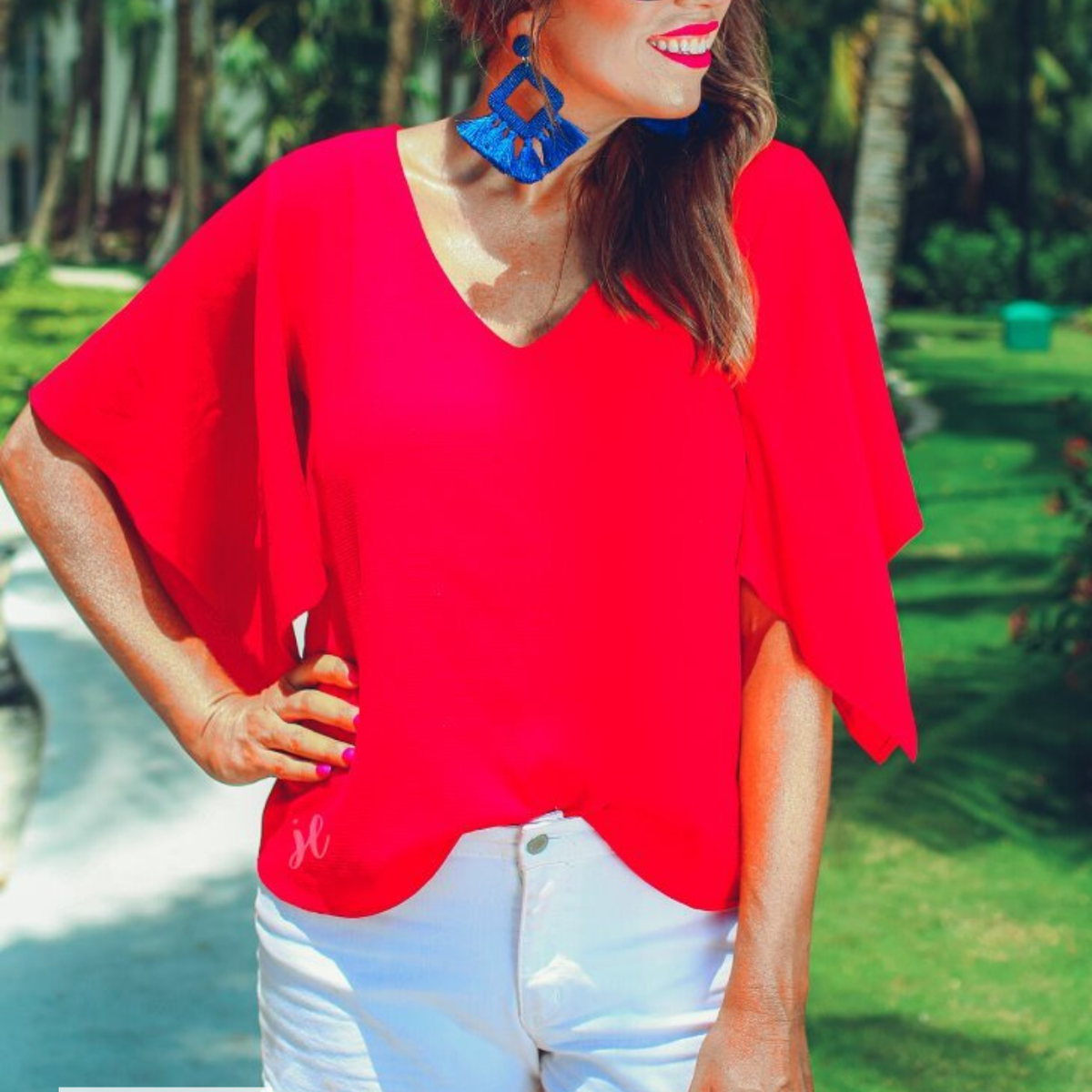 a red v-neck blouses crafted from lightweight textured fabric with asymmetrical half-flutter sleeves, front lining, and a relaxed fit, accented by a MADE IN USA watermark in the bottom left-hand corner
