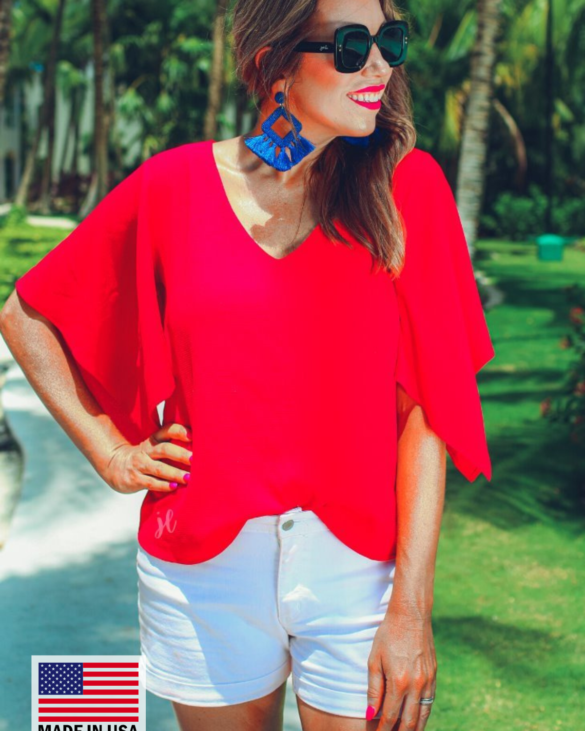 a red v-neck blouses crafted from lightweight textured fabric with asymmetrical half-flutter sleeves, front lining, and a relaxed fit, accented by a MADE IN USA watermark in the bottom left-hand corner