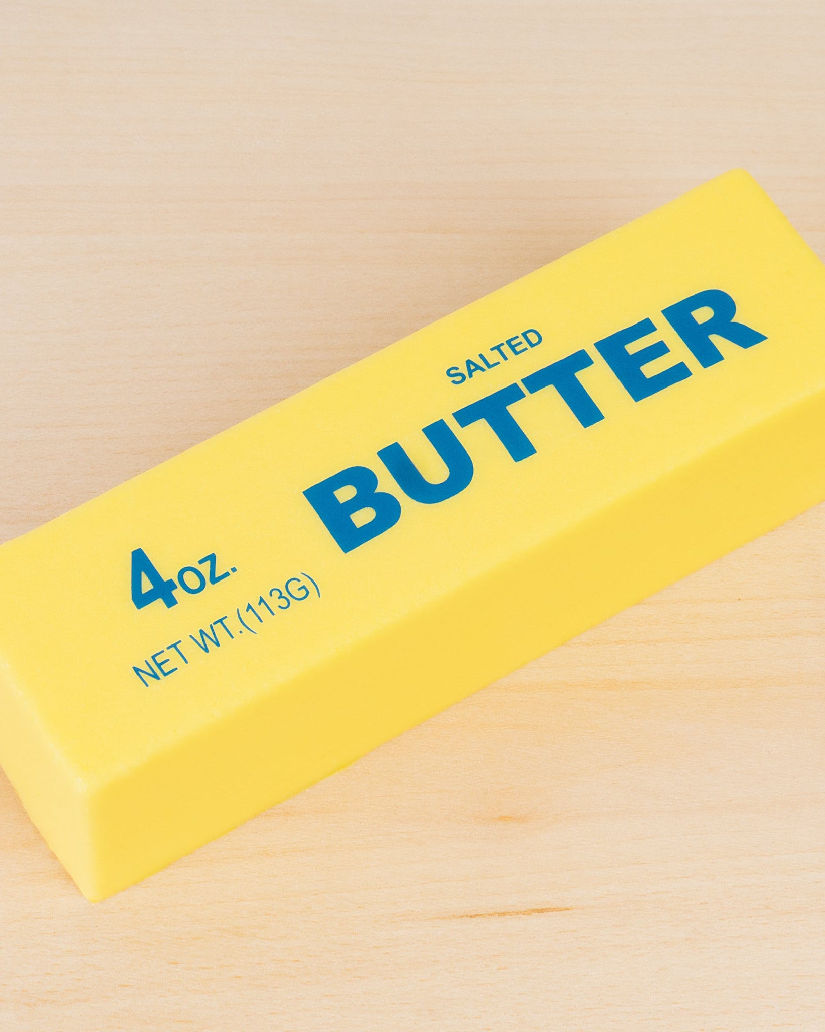 a 4oz yellow butter-stick foam fidget toy made from slow rise polyurethane (PU) foam with a soft texture, classic butter-inspired print, and individual packaging