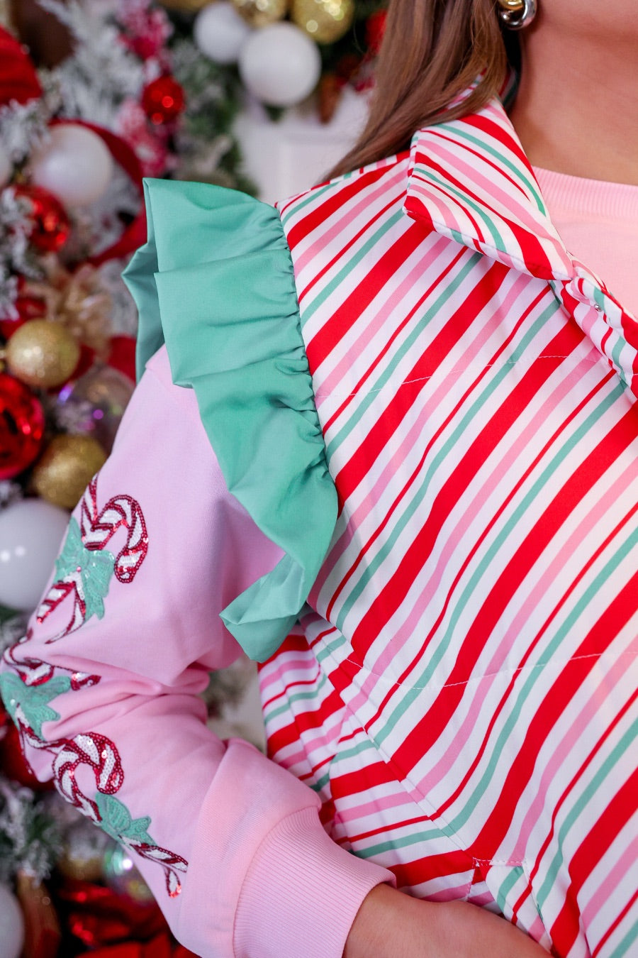 lightweight quilted puffer vest with a festive multicolor candy stripe pattern, snap-front closure, flattering fit, practical pockets, and whimsical teal ruffle shoulder detail