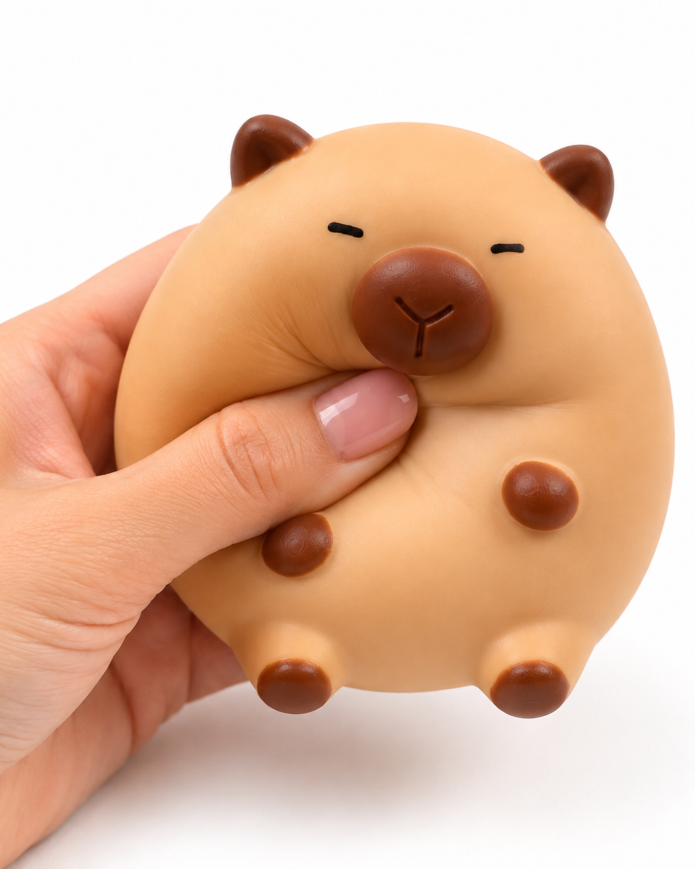 a capybara-inspired squishy toy with a rounded tan body, brown accent details, sleepy face, and smooth squeezable texture being squeezed