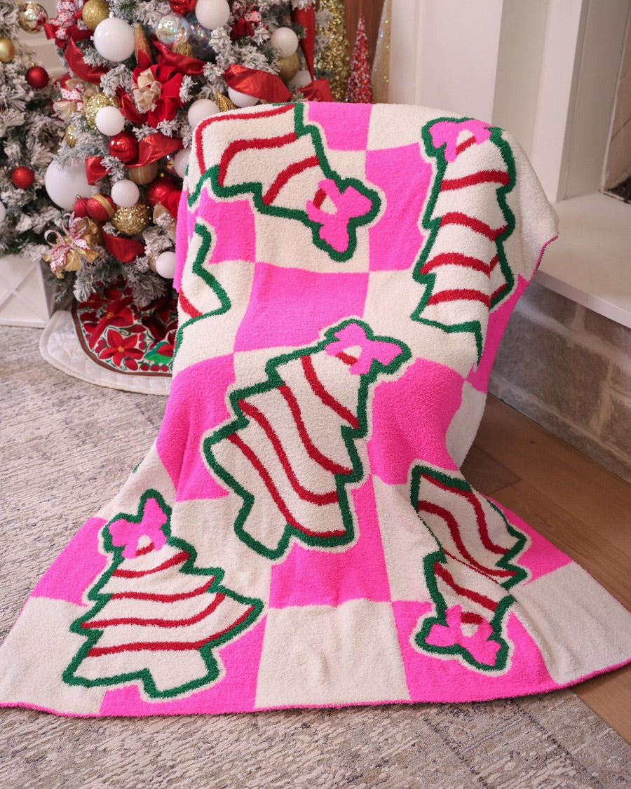 ultra-soft throw on a bold pink and white checkered background decorated with whimsical Christmas tree treats, each topped with an adorable pink bow