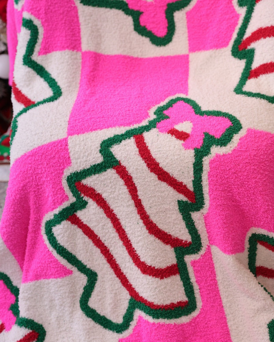 ultra-soft throw on a bold pink and white checkered background decorated with whimsical Christmas tree treats, each topped with an adorable pink bow