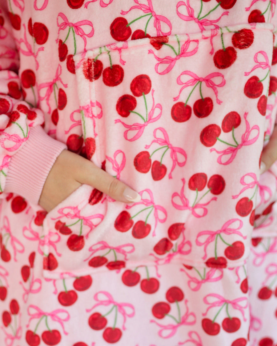 a blanket hoodie with roomy long sleeves finished with soft ribbed cuffs, a slouchy hood, drop shoulder, a kangaroo pouch on ultra plush fabric in Cherry Bomb (Pink)