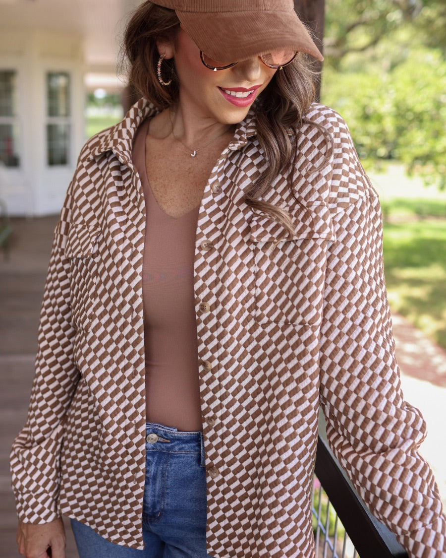 long-sleeve shacket with a foldable collar, button-up open front, and two chest pockets on a tan and white textured fabric